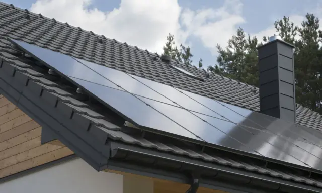 Nowoczesny dach z paneli fotowoltaicznych, szary komin i dachówka. Dom gotowy na zieloną energię.