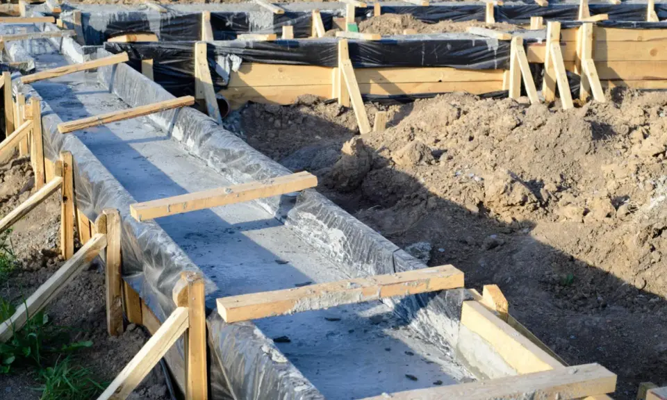 Budowa fundamentów krok po kroku: betonowanie ław fundamentowych w szalunkach z folią.