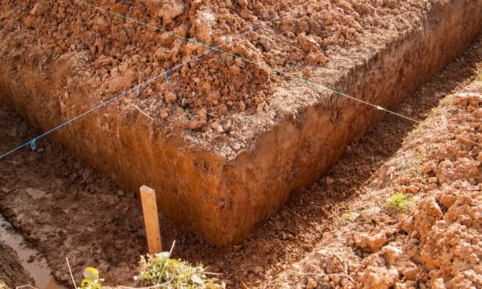 Wyznaczone wykopy pod fundamenty, z widocznymi nićmi wyznaczającymi linie i drewnianym palikiem.