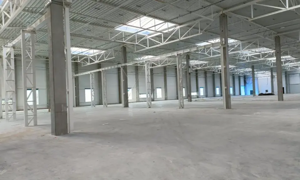 Wnętrze nowej hali magazynowej, betonowe słupy i stalowa konstrukcja dachu. Projekt hali magazynowej w trakcie realizacji.
