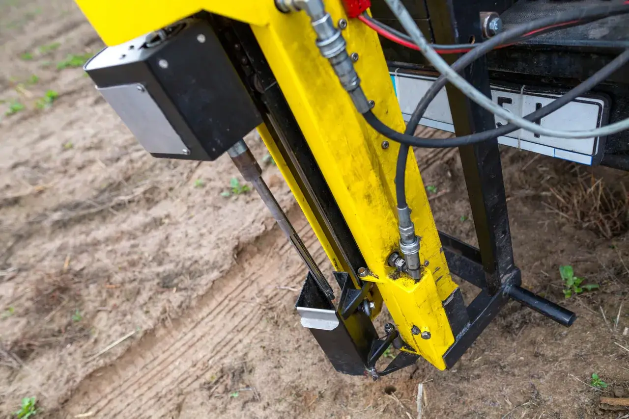 Żółta maszyna do badań geotechnicznych gruntu w akcji. Wiertło zagłębia się w ziemię, zbierając próbki do analizy.