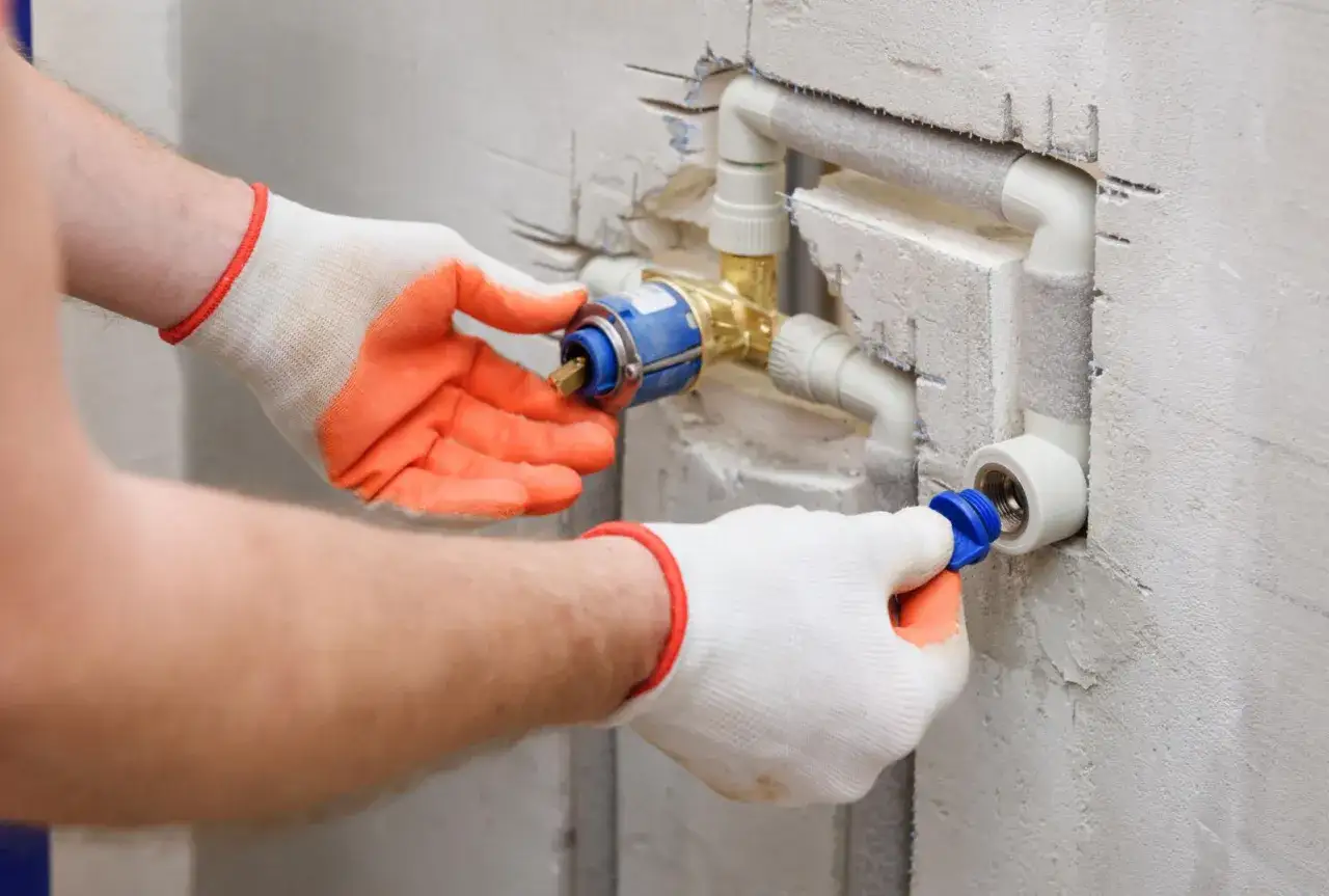 Instalator w rękawiczkach montuje zawór, który pomoże jak zwiększyć ciśnienie wody w instalacji.
