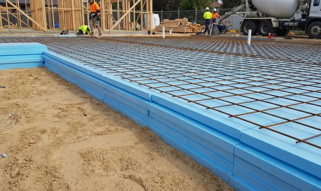 Styrodur pod płytę fundamentową ułożony na piasku, z siatką zbrojeniową gotową do zalania betonem.