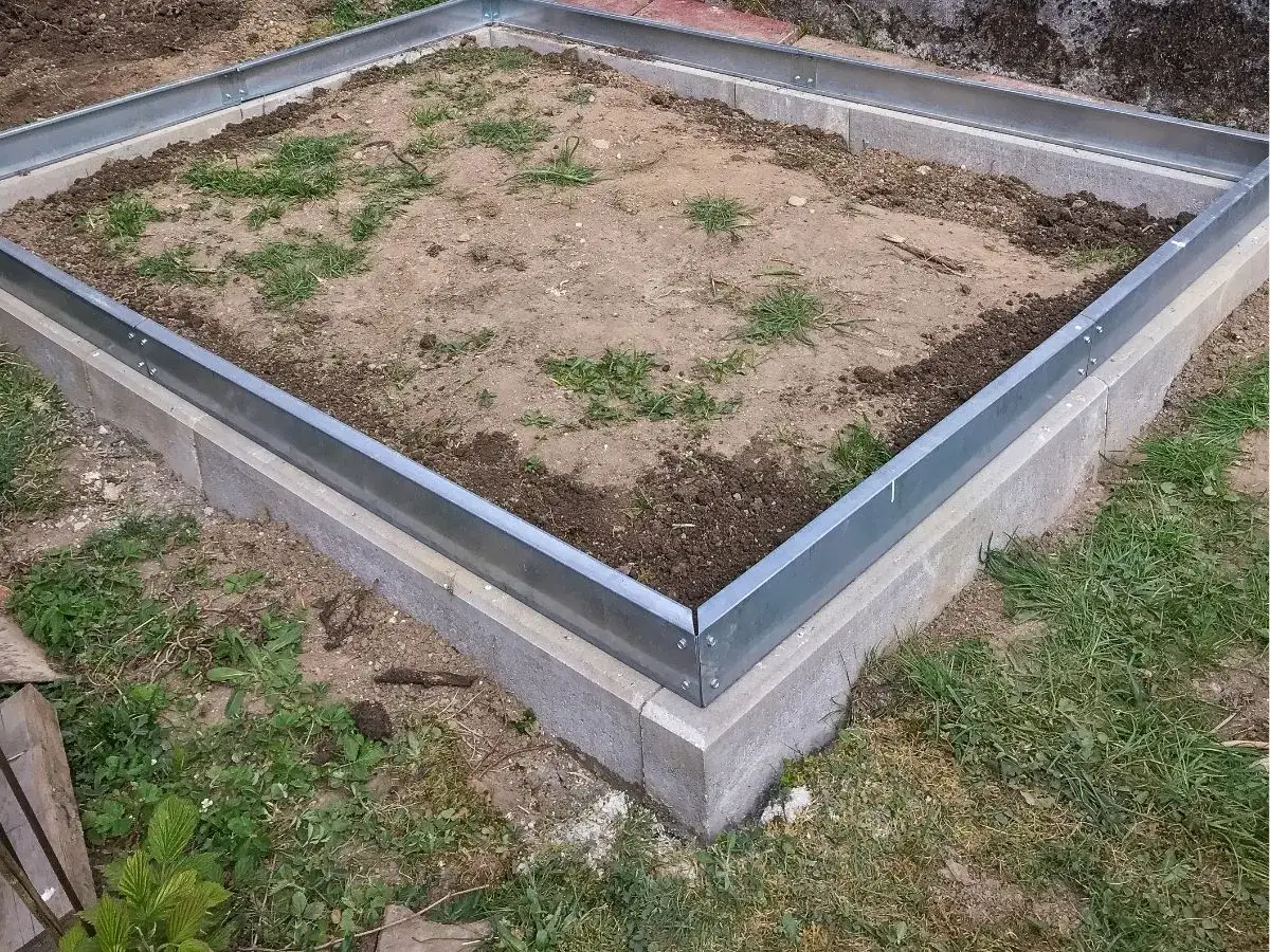 Solidny fundament z bloczków betonowych, gotowy pod budowę. Metalowa obudowa wyznacza kształt.