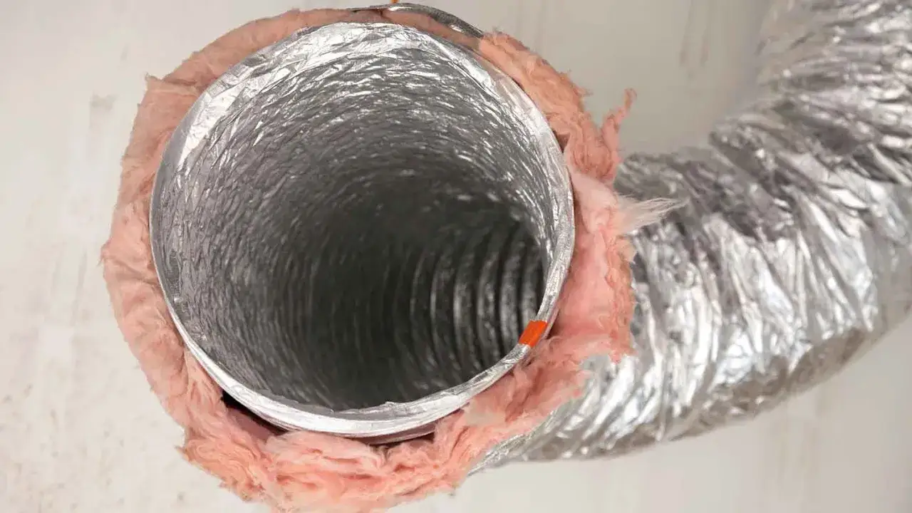 Elastyczny kanał wentylacyjny z folii aluminiowej, owinięty różową wełną mineralną dla izolacji.